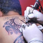 Cindy Parra utiliza pintura negra, pero también blanca para tatuarle un pez kói a Belfort Chávez. tatuadores 13