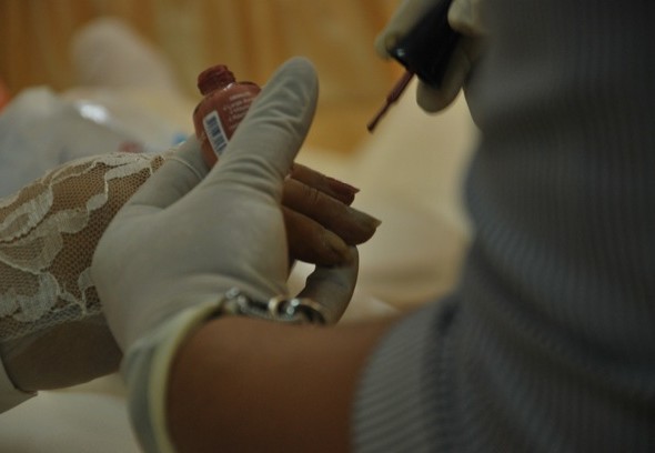 Por petición de los familiares Katiria Mejía pinta las uñas de una fallecida.