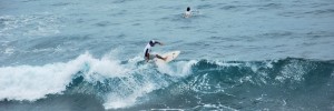 Felipe Rodríguez practica surf en la playa de la FAE en Salinas. Su hijo aparece atrás buscando una ola.